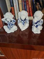 Front view of all three blue and white porcelain monkey figurines on shelf