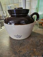 Front view showing two-tone glaze, handle, lid, and crown logo