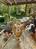 Full view of white and gold porcelain lidded urn on table