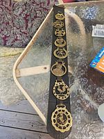 Full view of strap showing eight brass plaques on leather