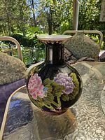 Front view of black porcelain vase with pink and purple floral enamel