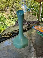 Front view of teal matte bud vase on table