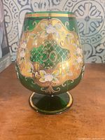 Full view of emerald green goblet showing front gilded cartouche and floral decoration