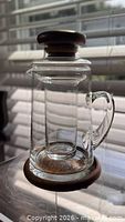 Front view of glass pitcher with teak lid and base