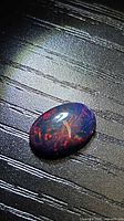 Oval black opal showing multicolour play-of-colour on dark body