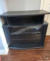 Front view of black TV stand showing glass doors closed