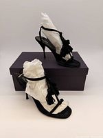 Pair of black suede Prada stiletto sandals displayed with purple Prada box