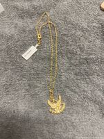 Full view of gold electroplated chain with attached Air Force eagle pendant laid on grey surface