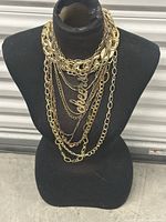 Front view of layered gold-tone necklaces on display bust