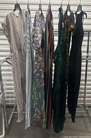 Seven assorted jumpsuits hanging on rack