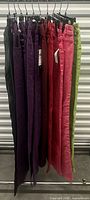 Side view of all ten pairs of colored jeans hanging on rack