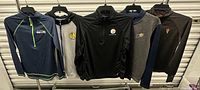 Group shot of all five team pullovers and hoodie on hangers