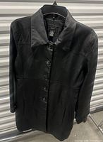 Front view of black leather jacket on hanger
