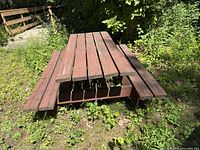 Three-quarter view of red wooden picnic table showing top slats and both benches