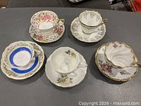 Five teacup and saucer sets front view on table