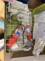 Top-down view of open stove showing burners, grate, two propane cylinders, hose