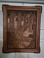Front view of the rectangular wooden relief carving showing deer in forest and ornate border