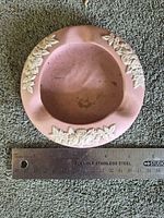Top view showing pink bisque ashtray with white floral relief and ruler indicating 5.5–6 in diameter