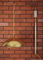 Full view of wall-mounted cantilever lamp showing brass arm, counterweight tube and dome shade