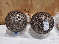 Two rust-finished metal spheres with cutout pattern on bubble wrap