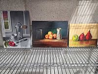 All three unframed signed paintings on canvas board displayed on shelf