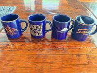 All four blue ceramic souvenir mugs displayed side by side
