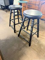 Two Thomasville black wood swivel counter stools full view