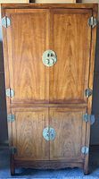 Full front view of closed armoire showing brass hardware, two-section design and carved base