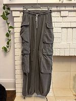 Front view of gray cargo jogger pants showing drawstring waist, cargo pockets, elastic cuffs