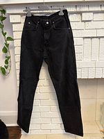 Front view of black Wrangler denim jeans hanging to show full length and leg cut