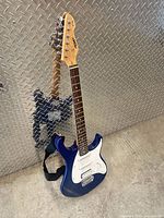 Full view of Peavey EXP blue electric guitar standing upright with strap attached