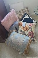 Group of seven assorted pillows arranged on floor
