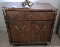 Front view showing drawer, doors, brass pulls, corner caps