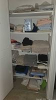 Closet shelves filled with folded towels, sheets, blankets and packaged linens