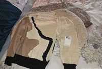Three sweaters stacked showing colors and styles