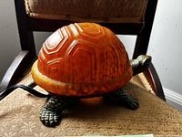 Side view of turtle lamp showing amber glass shell and metal base