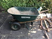 Side angle of the green Craftsman wheelbarrow showing the tire and frame.