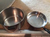Large metal pot and medium frying pan viewed from top and inside, showing interior condition