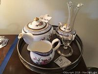 Tea set pieces including lidded teapot, creamer, sugar bowl on metal tray, along with glass bud vase with sterling base.