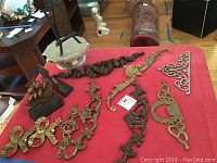 Overview of brass and metal decorative wall accents, brass hooks, metal ship bookends, and the resin pedestal with easel on red cloth