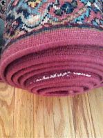 Close-up image of the rug runner's roll end showing red fabric binding that is loose.
