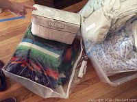 Pendleton blanket and two packs of linens on wooden floor, with clear packaging visible