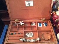Overview of brown jewelry box with multiple compartments containing various sterling silver jewelry pieces including rings, bracelets, cufflinks, and brooch.