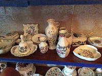Photo showing a variety of Royal Doulton china and bone china pieces on a shelf, including vases, dishes, and lidded containers with floral patterns.