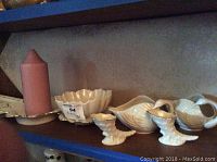 Shelf display of Lenox items including candle on dish, small scalloped bowl, two swan containers