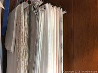Tablecloths and linens hanging on rack, showing texture, color variations and condition
