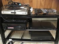 Front view of black metal stand with multiple electronic components including Dual turntable, Pioneer receiver, and other devices stacked on shelves.