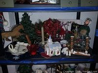 Front view of shelf holding assorted Christmas decorations including dishes, figurines, tree and wreath