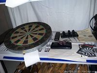 Full view of dartboard, darts, cases, and instructions on a table.