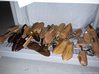 Group of vintage hardwood shoe stretchers and shoe trees in varying sizes and colors showing the entire lot
